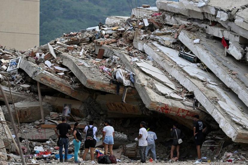 People stand amid the rubble of a collapsed building as they wait for news of relatives believed to be trapped under the debris in Caraballeda, La Guaira state, Venezuela, on July 9, 2026 following the June 24 earthquakes. The United Nations launched an urgent appeal on July 8, 2026 for nearly $300 million towards Venezuela earthquake relief operations as the death toll from the disaster rose to more than 3,800 people. Raul ARBOLEDA / AFP