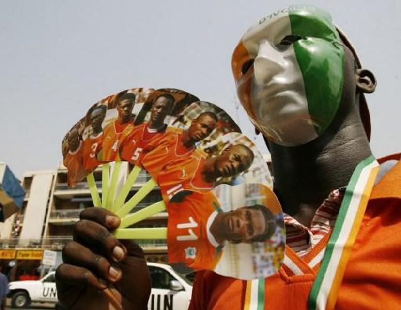 A supporter of the Elephants, the Ivorian national football team, wearing a mask with the Ivorian colours, waves a fan with portraits of the players 24 January 2008 in Abidjan.  Ghana's Michael Essien is relishing the prospect of coming up against his Chelsea teammate Didier Drogba's Ivory Coast in the African Nations Cup final. AFP PHOTO / KAMBOU SIA