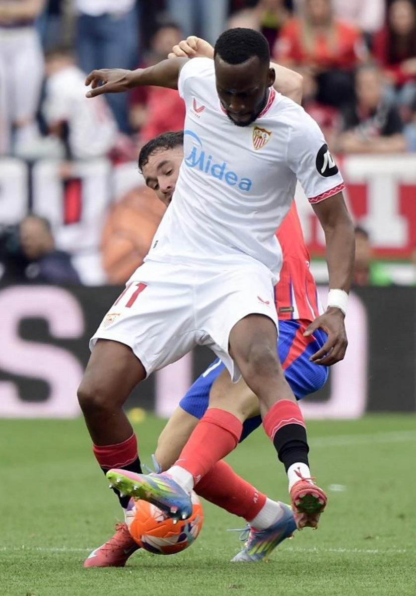 Atletico Madrid's Spanish defender #21 Javi Galan (BACK) and Sevilla's Belgian forward #11 Dodi Lukebakio fight for the ball during the Spanish league football match between Sevilla FC and Club Atletico de Madrid at the Ramon Sanchez Pizjuan stadium in Seville on April 6, 2025.  CRISTINA QUICLER / AFP