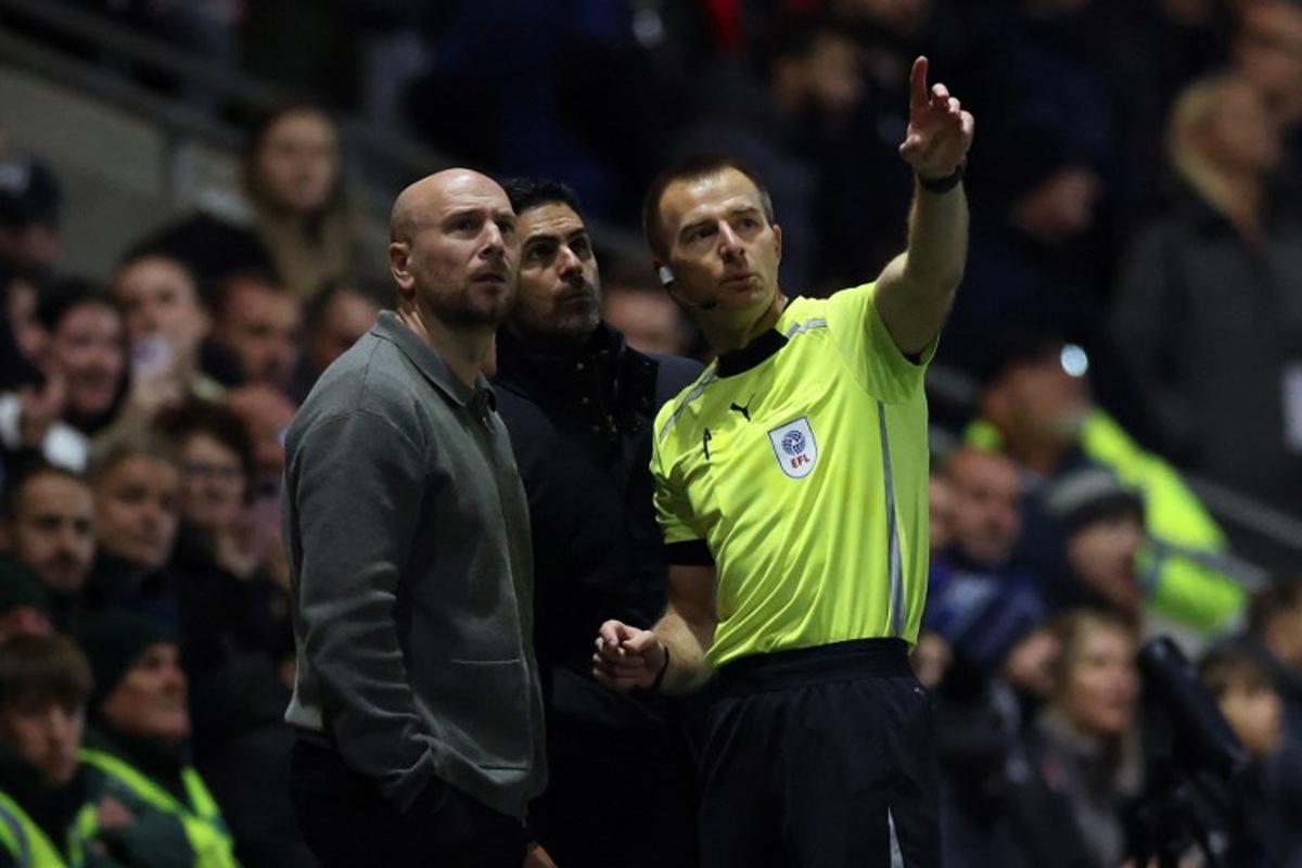 Referee Michael Salisbury (R) gestures towards a drone in the sky as he speaks to Arsenal's Spanish manager Mikel Arteta (C) and Fleetwood's English manager Matt Lawlor during the English League Cup fourth round football match between Fleetwood Town and Arsenal at Highbury Stadium in Fleetwood, north west England, on October 27, 2026.   Darren Staples / AFP