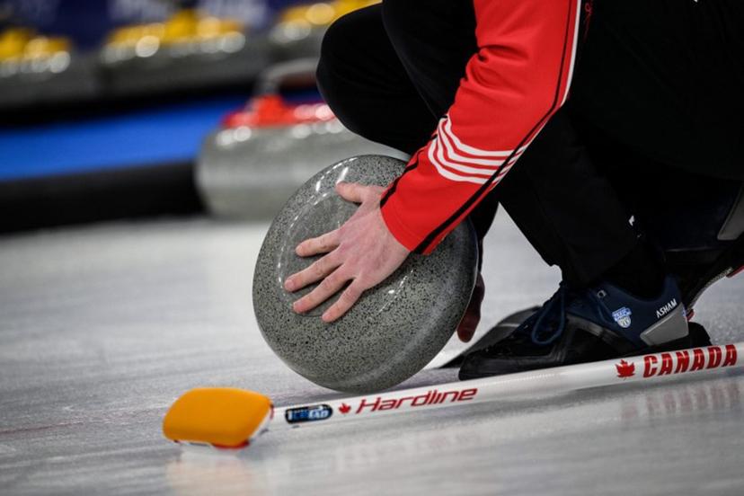 A Canada team member checks on the curling stone during the men's bronze medal game of the Beijing 2022 Winter Olympic Games curling competition between Canada and USA at the National Aquatics Centre in Beijing on February 18, 2022.  Jeff PACHOUD / AFP