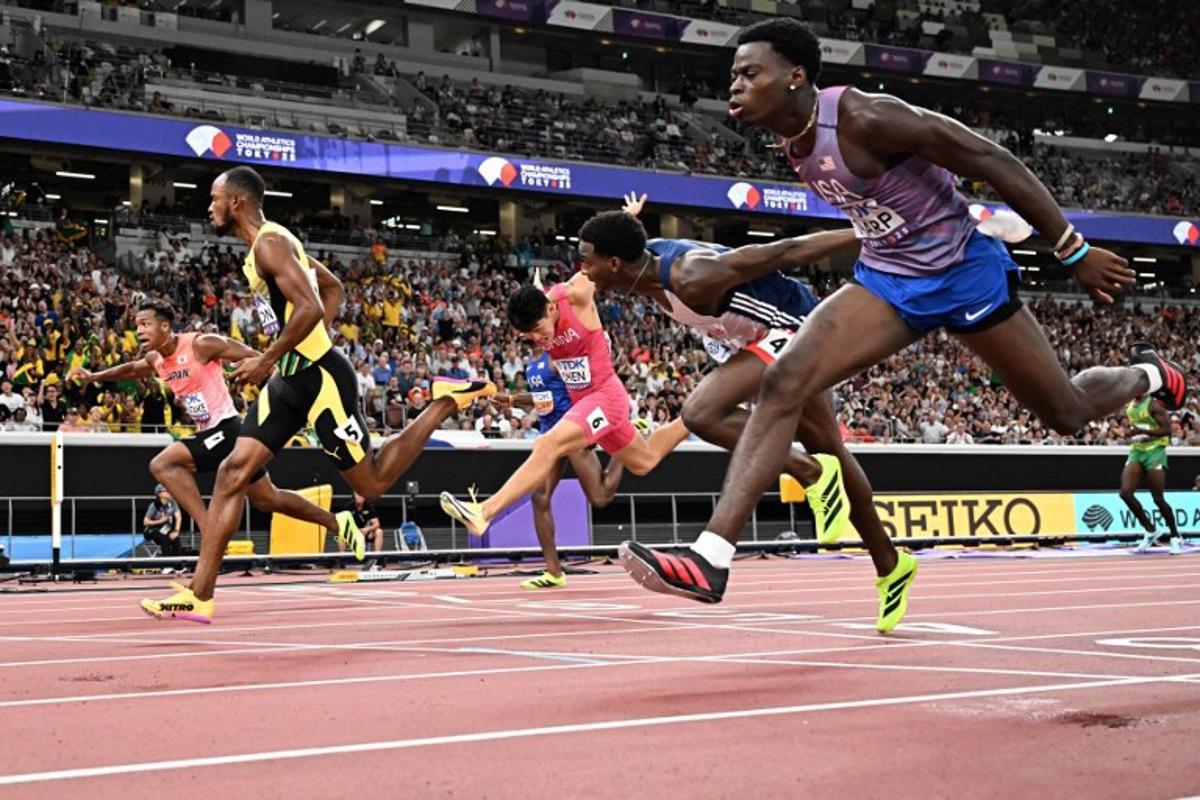 Athletes including US' athlete Ja'Kobe Tharp (R) and Jamaica's athlete Orlando Bennett (2nd L) cross the finish line in the men's 110m hurdles heats during the World Athletics Championships in Tokyo on September 15, 2025.  Jewel SAMAD / AFP