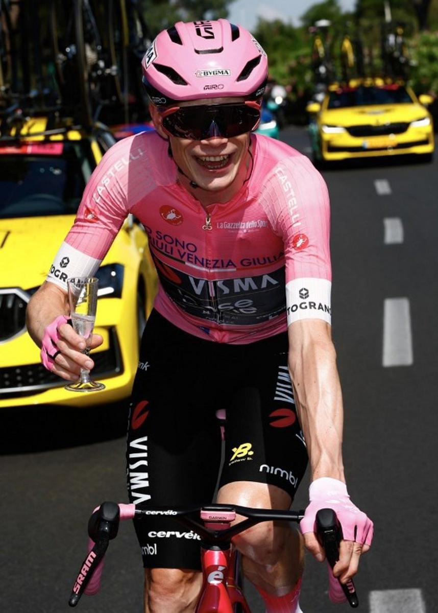 Team Visma Lease a Bike Danish rider Jonas Vingegaard wearing the overall leader's pink jersey holds a glass of sparkling wine during the 21th stage of the Giro d'Italia 2026 - Tour of Italy cycling race of 131km from Rome to Rome, Italy, on May 31, 2026.  Luca Bettini / AFP