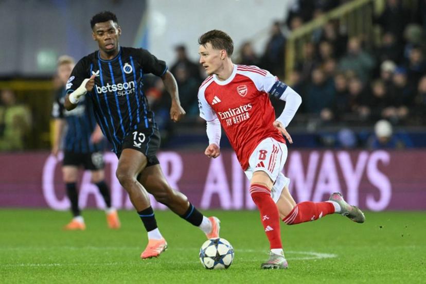 Arsenal's Norwegian midfielder #08 Martin Odegaard (R) runs with the ball during the UEFA Champions League, league phase - matchday 6, football match between Club Brugge and Arsenal at the Jan Breydel stadium in Bruges on December 10, 2025.  NICOLAS TUCAT / AFP