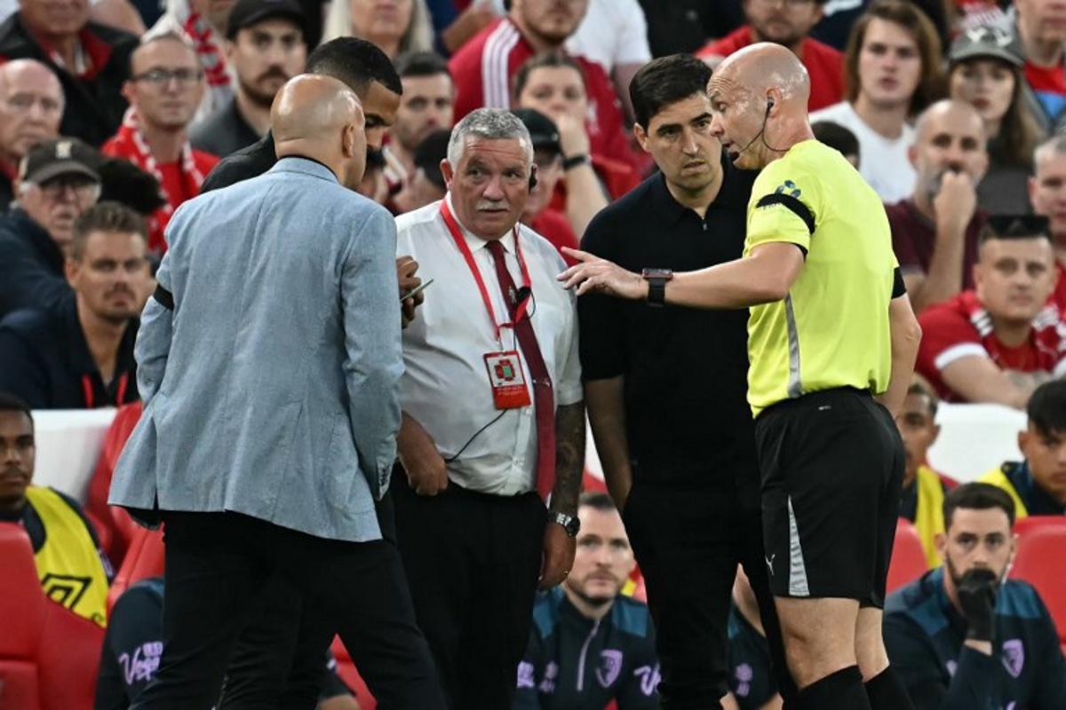 English referee Anthony Taylor (R) speaks with both coaches and the stadium safety officer after a member of the crowd shouted abuse at Bournemouth's Ghanaian striker #24 Antoine Semenyo during the English Premier League football match between Liverpool and Bournemouth at Anfield in Liverpool, north west England on August 15, 2025.  Paul ELLIS / AFP