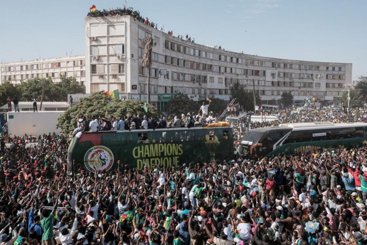 (FILES) Supporters cheer as the Senegalese football players ride on a bus during a trophy parade in the streets of Dakar on January 20, 2026 as they celebrate Senegal winning the Africa Cup of Nations (CAN) that was hosted in Morocco. Senegal football fans slammed AFCON'S decision to strip the country of its Africa Cup of Nations title and give it to Morocco, calling the move a "disgrace for Africa" as they woke up to the news Wednesday. Gora Ndiaye, a resident of Dakar who works as a chauffeur, told AFP he felt like he had "been hit over the head" when he heard the news on the radio. The Confederation of African Football (CAF) sensationally stripped Senegal of their title late Tuesday, citing regulations about leaving the field, which members did during the end of the final two months ago. GUY PETERSON / AFP