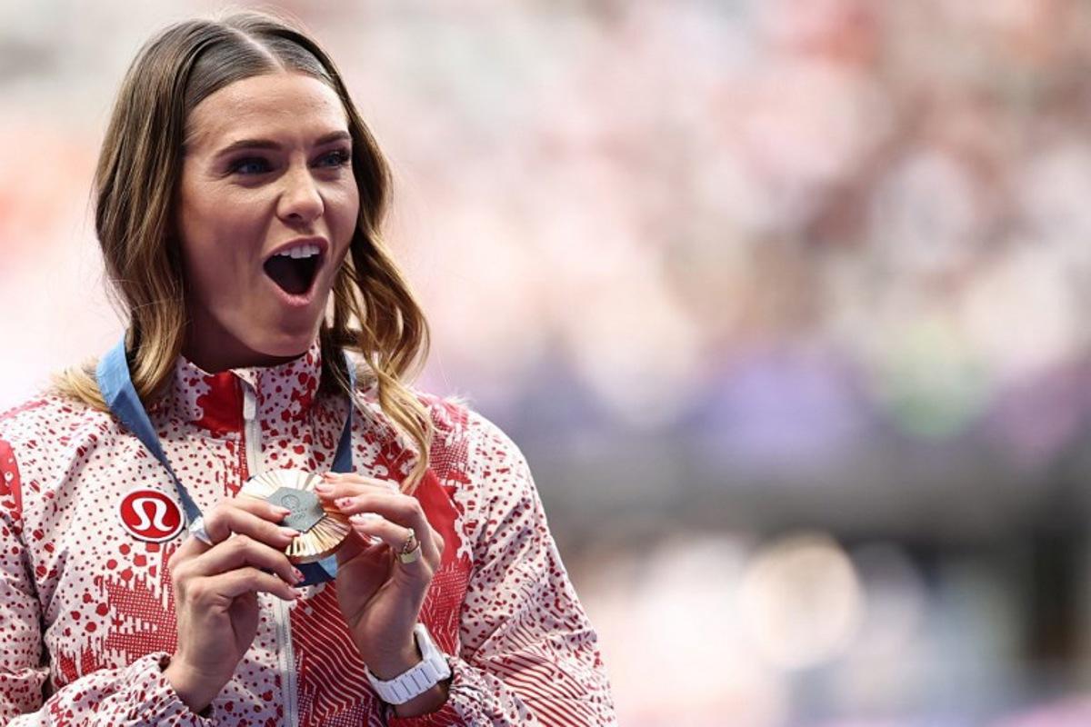 Bronze medallist Canada's Alysha Newman celebrates on the podium during the victory ceremony for the women's pole vault final athletics event at the Paris 2024 Olympic Games at Stade de France in Saint-Denis, north of Paris, on August 8, 2024. Anne-Christine POUJOULAT / AFP