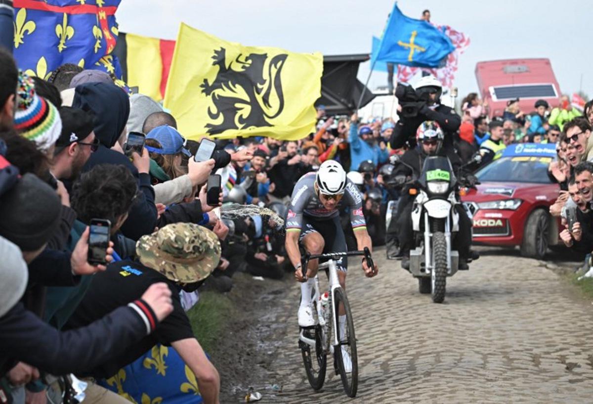 A spectator spills liquid as Alpecin-Deceuninck's Dutch rider Mathieu van der Poel cycles during the 122nd edition of the Paris-Roubaix one-day classic cycling race, 259,2 km between Compiegne and Roubaix, northern France on April 13, 2025. Bernard PAPON / POOL / AFP