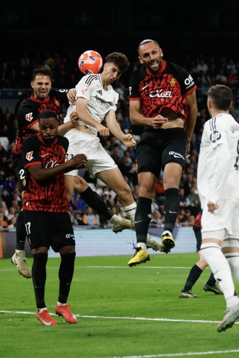 Real Madrid's Spanish defender #31 Jacobo Ramon (C) and Real Mallorca's Kosovo forward #07 Vedat Muriqi go for a header during the Spanish league football match between Real Madrid CF and RCD Mallorca at the Santiago Bernabeu Stadium in Madrid, on May 14, 2025. Pierre-Philippe MARCOU / AFP