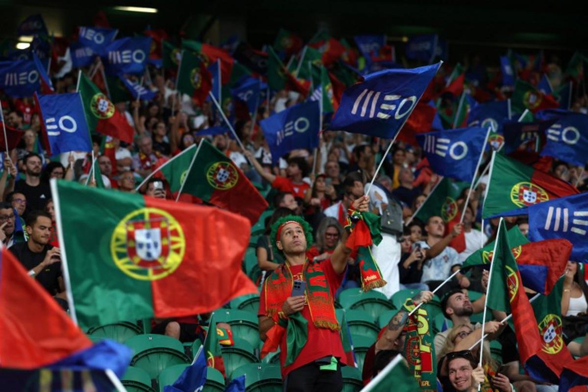 Portugal fans wave flags as they wait for the start of the 2026 World Cup qualifier Europe zone group F football match between Portugal and Ireland at Jose Alvalade stadium in Lisbon on October 11, 2025. PATRICIA DE MELO MOREIRA / AFP