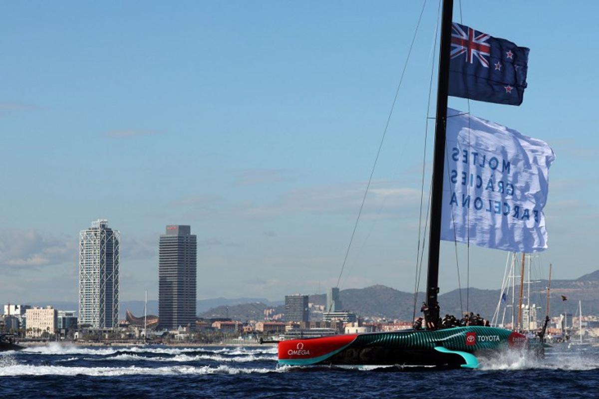 Members of the crew of defender Emirates Team New Zealand hoist a flagf reading in Catalan "Thanks a lot Barcelona" as they celebrate winning the Louis Vuitton 37th America's Cup Match, in Barcelona on October 19, 2024. LLUIS GENE / AFP