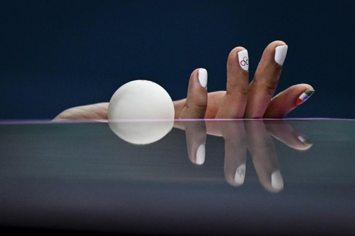 the hand and nails decorated with the Olympic Rings and the Indian flag is pictured as India's Manika Batra holds the ball prior to serve against France's Prithika Pavade during their women's table tennis singles round of 32 at the Paris 2024 Olympic Games at the South Paris Arena in Paris on July 29, 2024. WANG Zhao / AFP
