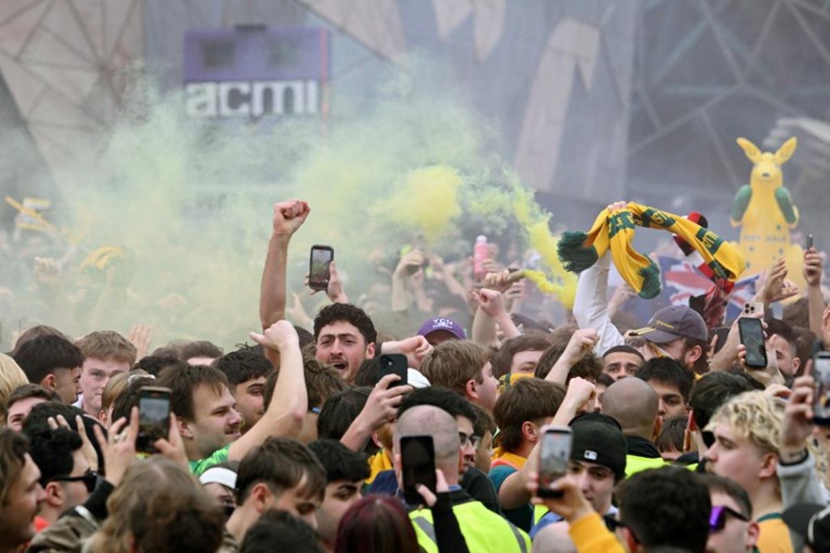 Football fans celebrate Australia's goal as they watch a broadcast of the FIFA World Cup 2026 Group D match between Australia and Turkey on a giant screen during a public viewing event in Melbourne on June 14, 2026. WILLIAM WEST / AFP