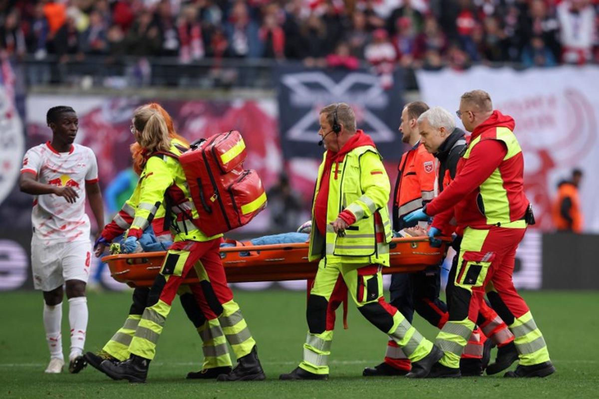 Leipzig's Malian midfielder #08 Amadou Haidara (L) checks on Leipzig's Hungarian goalkeeper #01 Peter Gulacsi who is stretchered off after sustaining an injury during the German first division Bundesliga football match between RB Leipzig and Holstein Kiel in Leipzig, eastern Germany on April 19, 2025. RONNY HARTMANN / AFP