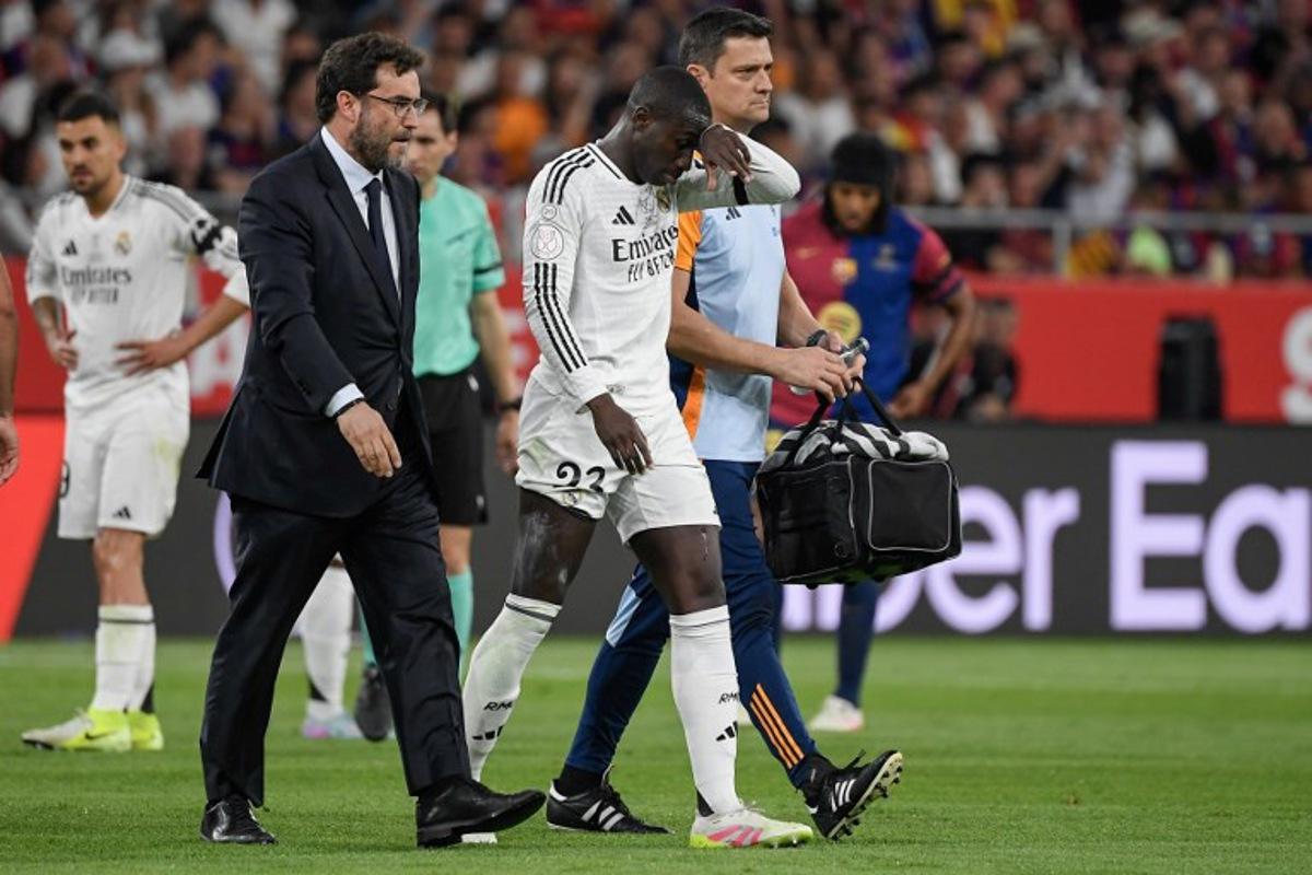 Real Madrid's French defender #23 Ferland Mendy leaves the pitch after resulting injured during the Spanish Cup, Copa del Rey (King's Cup) final football match between FC Barcelona and Real Madrid CF at La Cartuja stadium in Seville on April 26, 2025. Josep LAGO / AFP