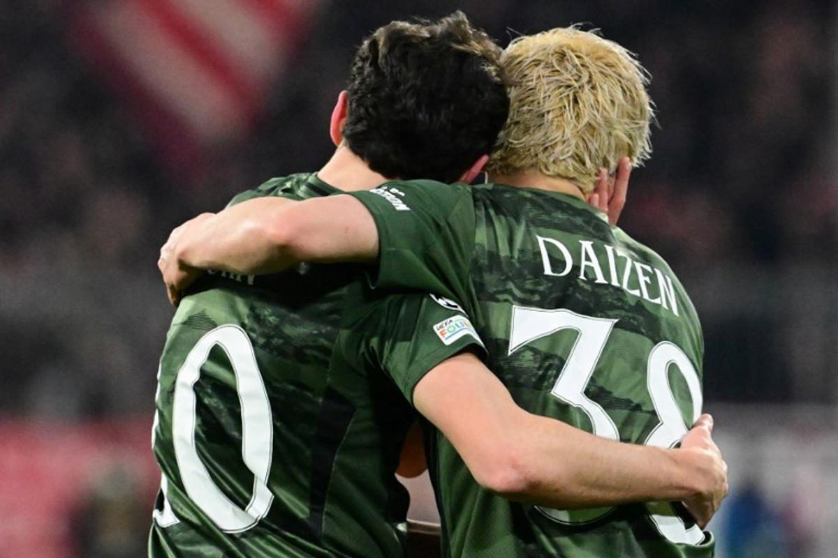 Celtic's German forward #10 Nicolas Kuehn (L) celebrates scoring the opening goal with his teammate Celtic's Japanese forward #38 Daizen Maeda during the UEFA Champions League second-leg, knockout phase play-off match FC Bayern Munich vs Celtic on February 18, 2025 in Munich. Tobias SCHWARZ / AFP