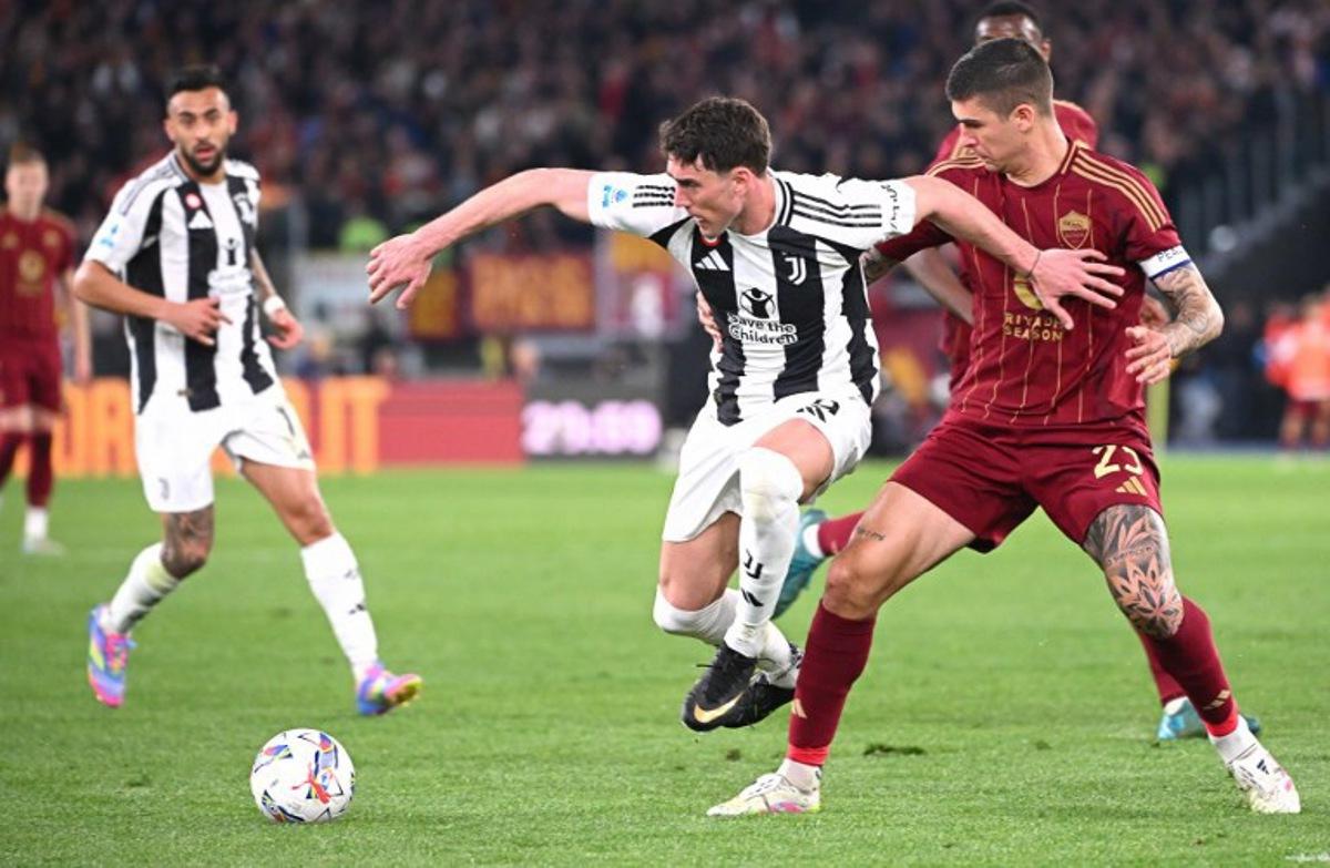 Juventus' Serbian forward #9 Dusan Vlahovic (C) fights for the ball with Roma's Italian defender #23 Gianluca Mancini (R) during the Italian Serie A football match AS Roma vs Juventus at Olympic stadium in Rome on April 6, 2025. Alberto PIZZOLI / AFP