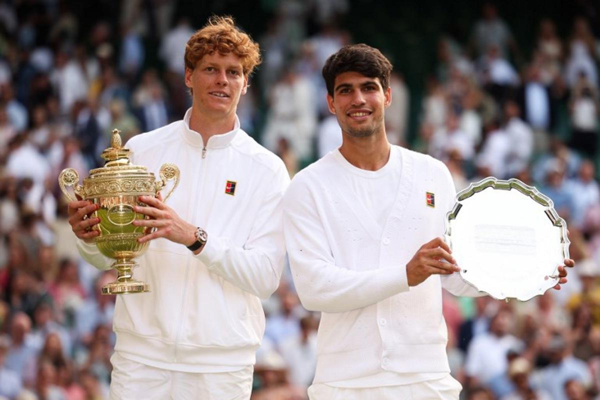 Italy's Jannik Sinner (L) holding the winner's trophy and second-placed Spain's Carlos Alcaraz pose for pictures during the price ceremony at the end of their men's singles final tennis match on the fourteenth day of the 2025 Wimbledon Championships at The All England Lawn Tennis and Croquet Club in Wimbledon, southwest London, on July 13, 2025. HENRY NICHOLLS / AFP