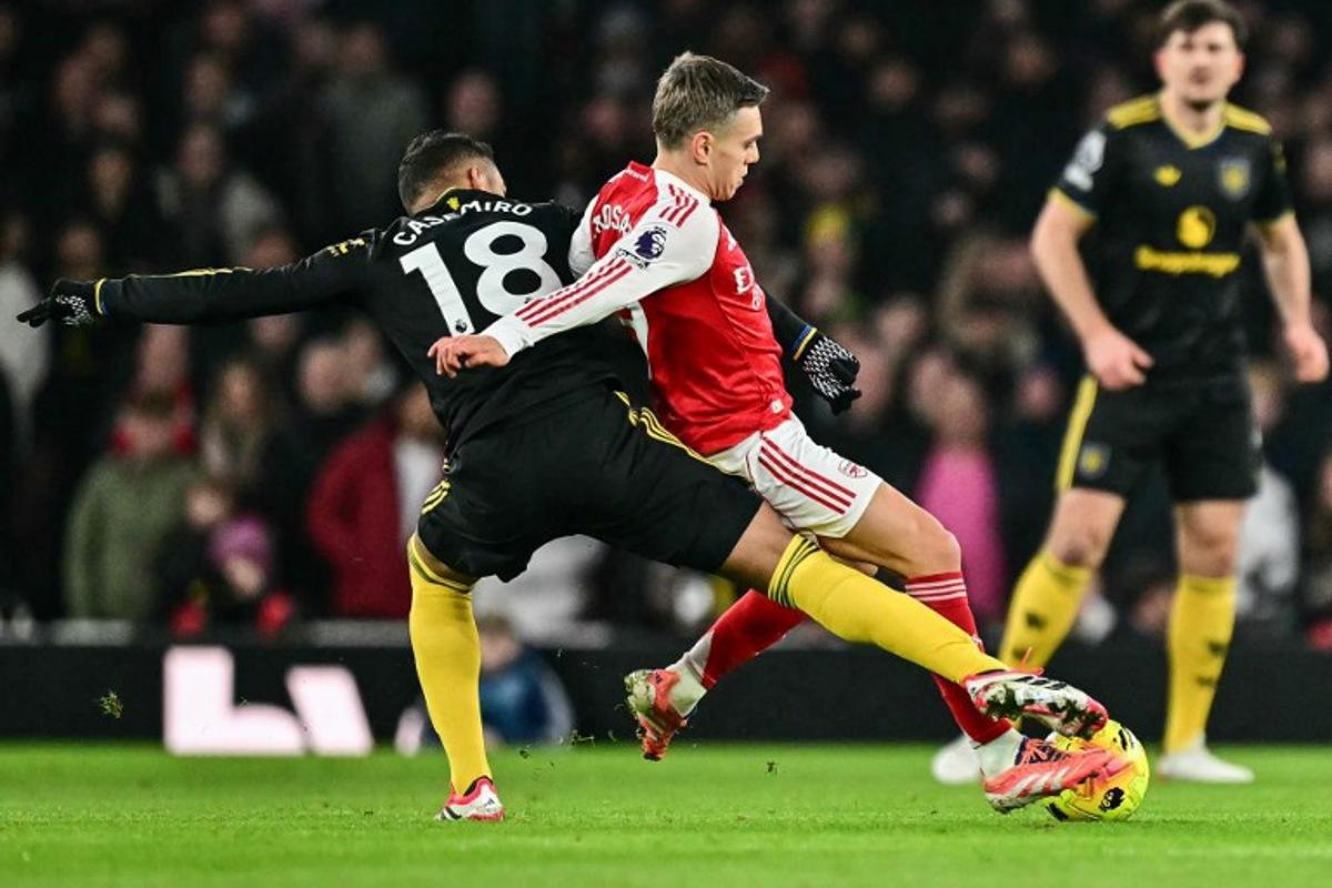 Manchester United's Brazilian midfielder #18 Casemiro (L) brings down Arsenal's Belgian midfielder #19 Leandro Trossard (C) for a free kick during the English Premier League football match between Arsenal and Manchester United at the Emirates Stadium in London on January 25, 2026. Ben STANSALL / AFP