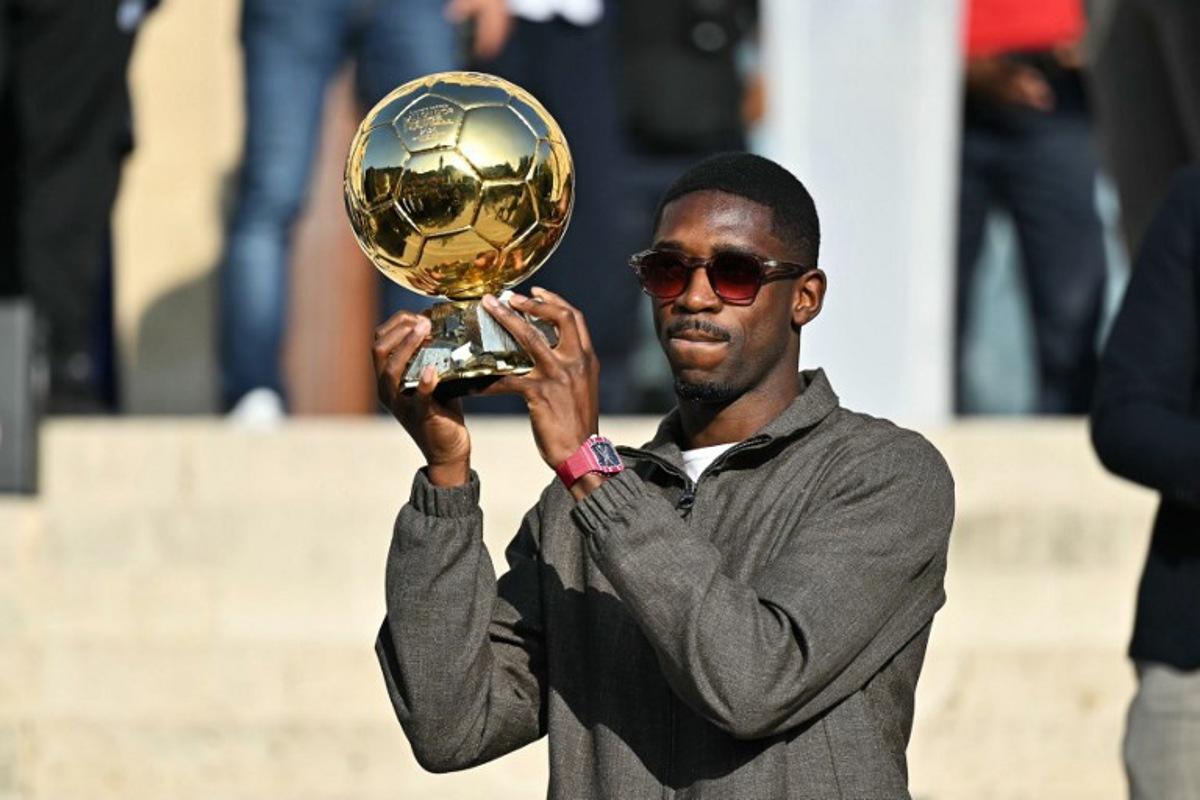 Paris Saint-Germain's French forward and 2025 Ballon d'Or winner Ousmane Dembele displays his trophy during a presentation ceremony at the City Hall in Evreux, his hometown and where he started playing club football, on October 12, 2025. LOU BENOIST / AFP