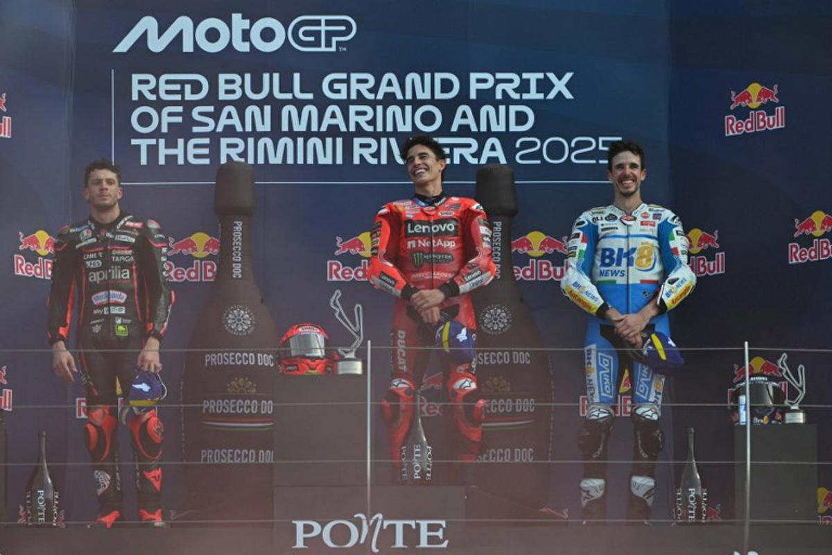 Ducati Lenovo Team's Spanish MotoGP rider Marc Marquez celebrates his victory on the podium next to Aprilia Racing team's Italian MotoGP rider Marco Bezzecchi (L) and BK8 Gresini Racing MotoGP team's Spanish MotoGP rider Alex Marquez (R) after the San Marino Moto GP Grand Prix at the Misano World Circuit Marco Simoncelli, in Misano Adriatico, northern Italy, on September 14, 2025. Andreas SOLARO / AFP