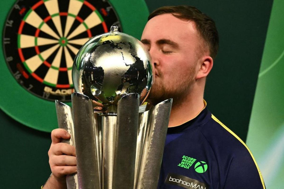 England's Luke Littler kisses the Sid Waddell Trophy after victory over Netherlands' Michael van Gerwen in the PDC World Darts Championship final, at Alexandra Palace in London on January 3, 2025. Luke Littler became darts' youngest world champion at just 17 after thrashing three-time winner Michael van Gerwen in front of an adoring home crowd at London's Alexandra Palace on Friday. This time there was no stopping "Luke the Nuke" as he stormed past Dutchman Van Gerwen by seven sets to three. Ben STANSALL / AFP