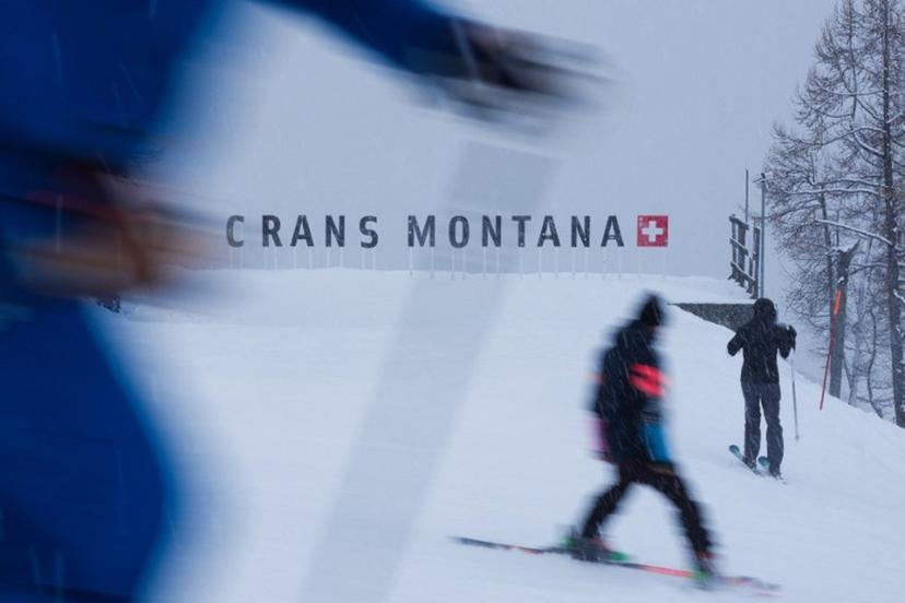Skiers ski past a logo of Crans Montana on the sidelines of the women's downhill race part of the FIS Alpine Ski World Cup 2025-2026, in Crans Montana, Switzerland, on January 30, 2026. Maxime Schmid / AFP