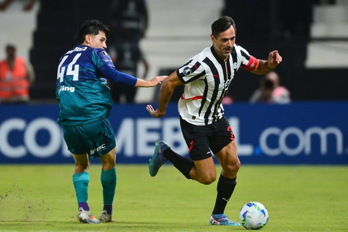 Talleres' defender #44 Santiago Fernandez and Libertad's forward #24 Roque Santa Cruz fight for the ball during the Copa Libertadores group stage football match between Paraguay's Libertad and Argentina's Talleres de Cordoba, at the La Huerta stadium in Asuncion, on April 8, 2025. DANIEL DUARTE / AFP