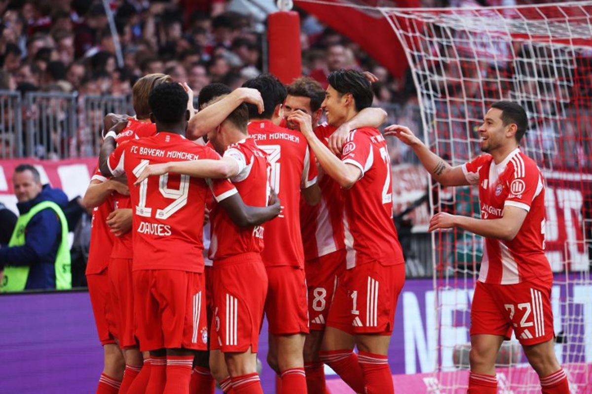 Bayern Munich's English forward #09 Harry Kane (L) celebrates with team mates after scoring the 4-1 goal as fans cheer in the background during the German first division Bundesliga football match between FC Bayern Munich and VfB Stuttgart in Munich, southern Germany, on April 19, 2026. Karl-Josef HILDENBRAND / AFP