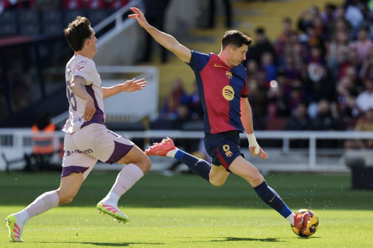 Barcelona's Polish forward #09 Robert Lewandowski (R) shoots challenged by Girona's Dutch midfielder #06 Donny Van de Beek during the Spanish league football match between FC Barcelona and Girona FC at the Estadi Olimpic Lluis Companys in Barcelona on March 30, 2025. LLUIS GENE / AFP