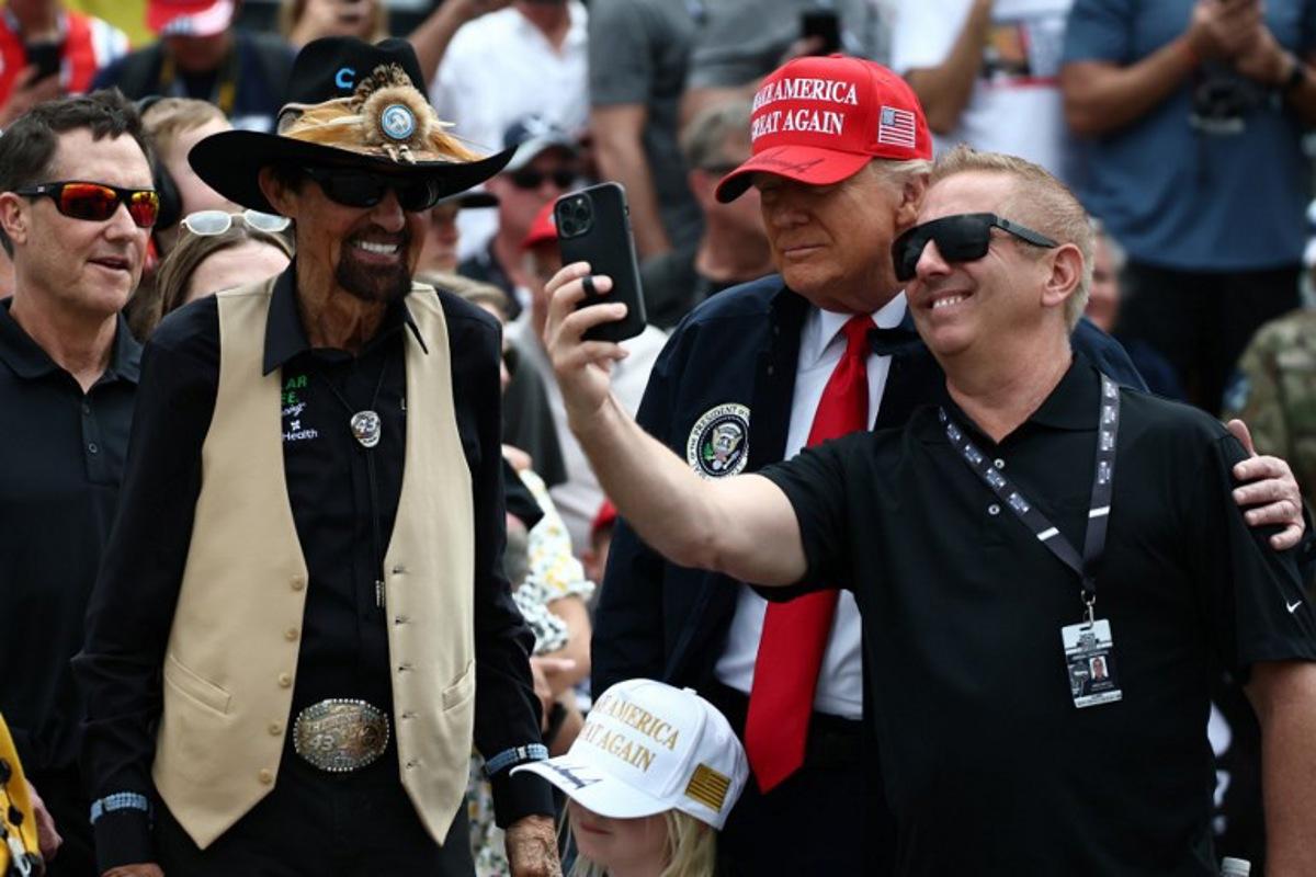 US PPresident Donald Trump takes a selfie with former NASCAR Cup series driver, Greg Biffle (R) and NASCAR Hall of Famer, Richard Petty prior to the NASCAR Cup Series Daytona 500 at Daytona International Speedway on February 16, 2025 in Daytona Beach, Florida. Chris Graythen / POOL / AFP