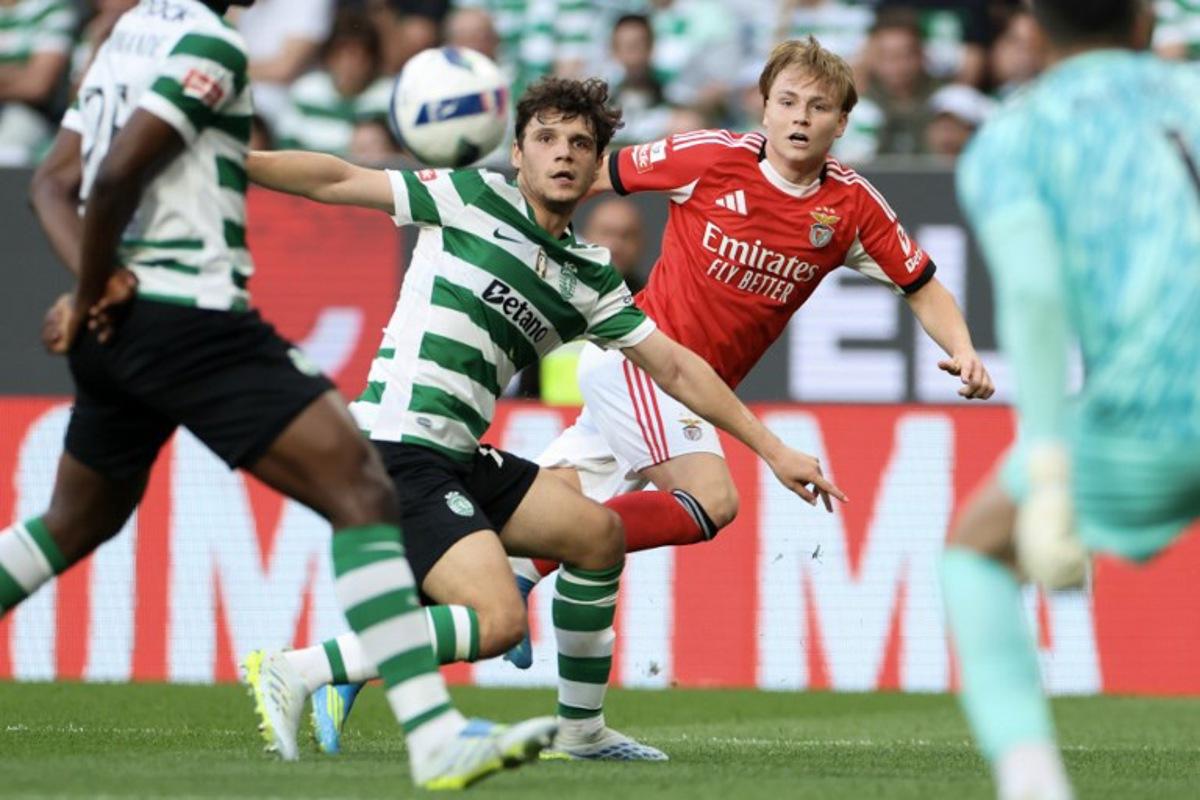 SL Benfica's Norwegian forward #21 Andreas Schjelderup (R) wathces the ball challenged by Sporting Lisbon's Portuguese defender #72 Eduardo Quaresma during the Portuguese League football match between Sporting CP and SL Benfica at Jose Alvalade stadium in Lisbon, on April 19, 2026. PATRICIA DE MELO MOREIRA / AFP