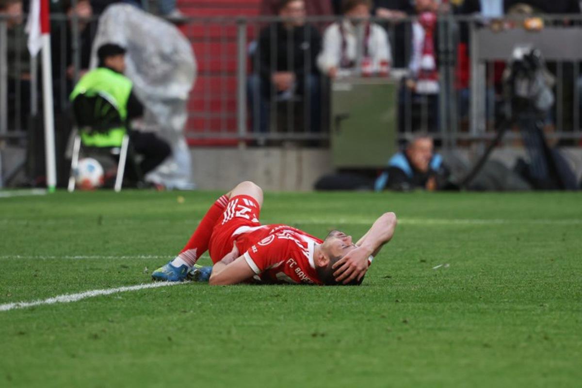 Bayern Munich's Portuguese defender #22 Raphael Guerreiro reacts in pain on the ground during the German first division Bundesliga football match between FC Bayern Munich and VfB Stuttgart in Munich, southern Germany, on April 19, 2026. Karl-Josef HILDENBRAND / AFP