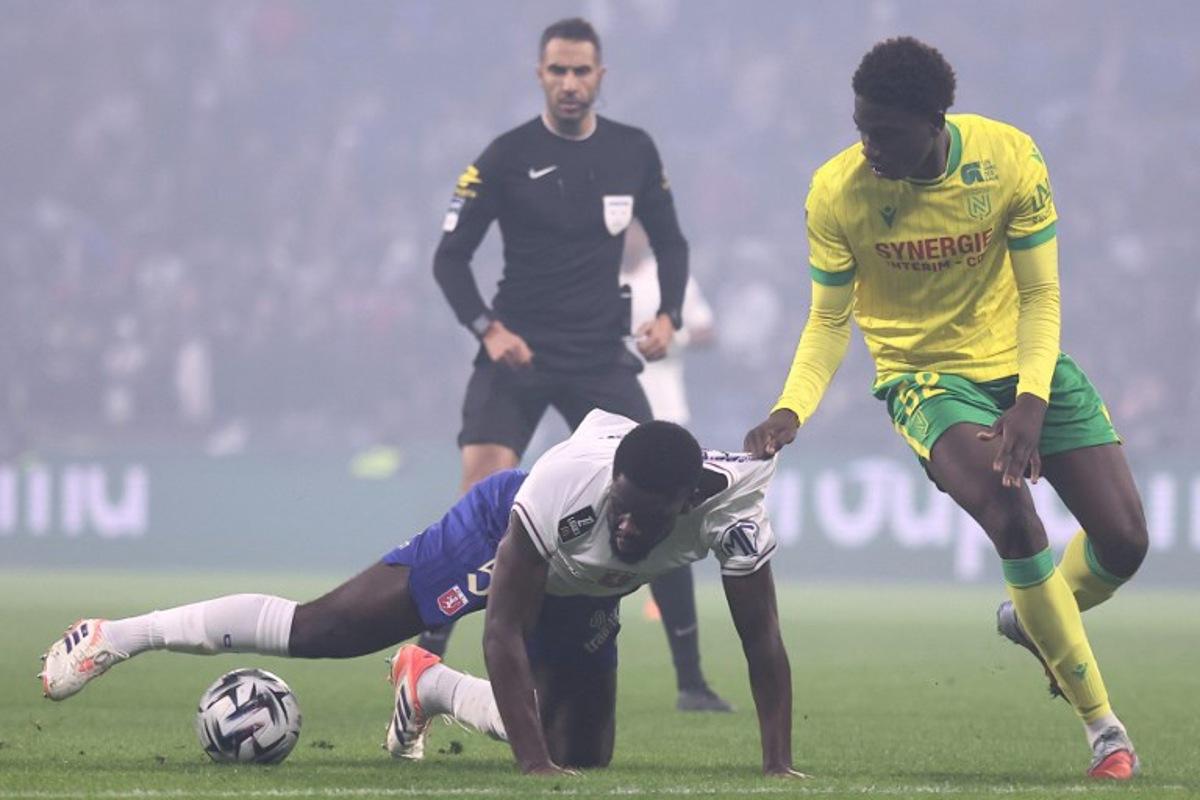 Lyon's Belgian midfielder #05 Orel Mangala (down) fights for the ball with Nantes' French midfielder #52 Bahmed Deuff (R) during the French L1 football match between Olympique Lyonnais (OL) and FC Nantes at the Parc Olympique Lyonnais stadium in Decines-Charpieu, central-eastern France on November 30, 2025. Alex MARTIN / AFP