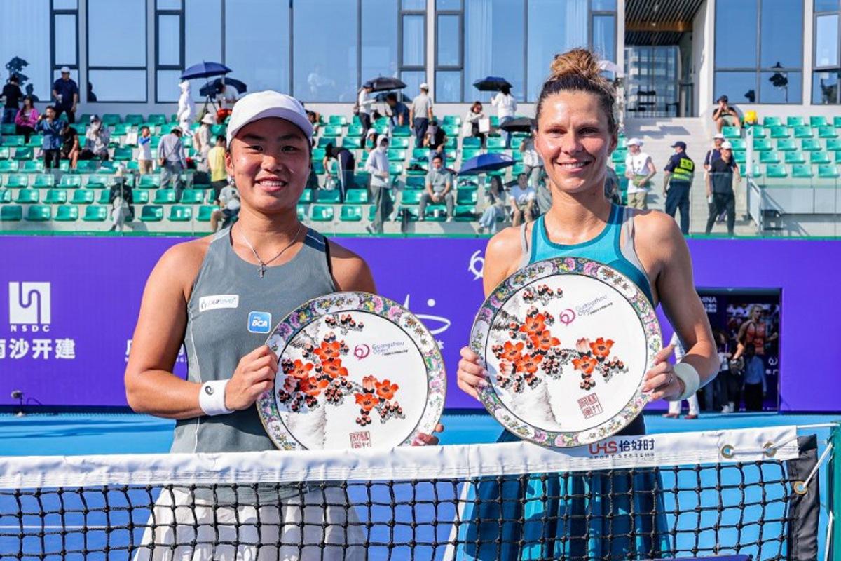 Winners Indonesia's Janice Tjen (L) and Poland's Katarzyna Piter pose with their women's doubles trophies after winning against Hong Kong's Eudice Chong and Taiwan's Liang En-shuo during an award ceremony at the Guangzhou Open tennis tournament in Guangzhou, southern China's Guangdong province on October 26, 2025. STR / AFP
