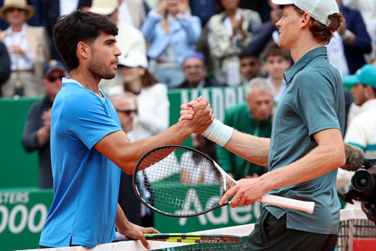 Italy's Jannik Sinner (R) shakes hands with Spain's Carlos Alcaraz after winning the Monte Carlo ATP Masters Series Tournament final tennis match on Court Rainier III at the Monte-Carlo Country Club in Roquebrune-Cap-Martin, south-eastern France on April 12, 2026. Valery HACHE / AFP