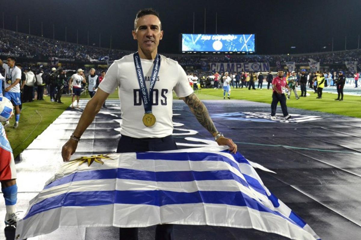 Cruz Azul's Uruguayan interim coach Vicente Sanchez poses with an Uruguayan flag after winning the CONCACAF Champions Cup final football match between Mexico's Cruz Azul and Canada's Vancouver Whitecaps at the Olimpico Universitario Stadium in Mexico City on June 1, 2025. Victor CRUZ / AFP