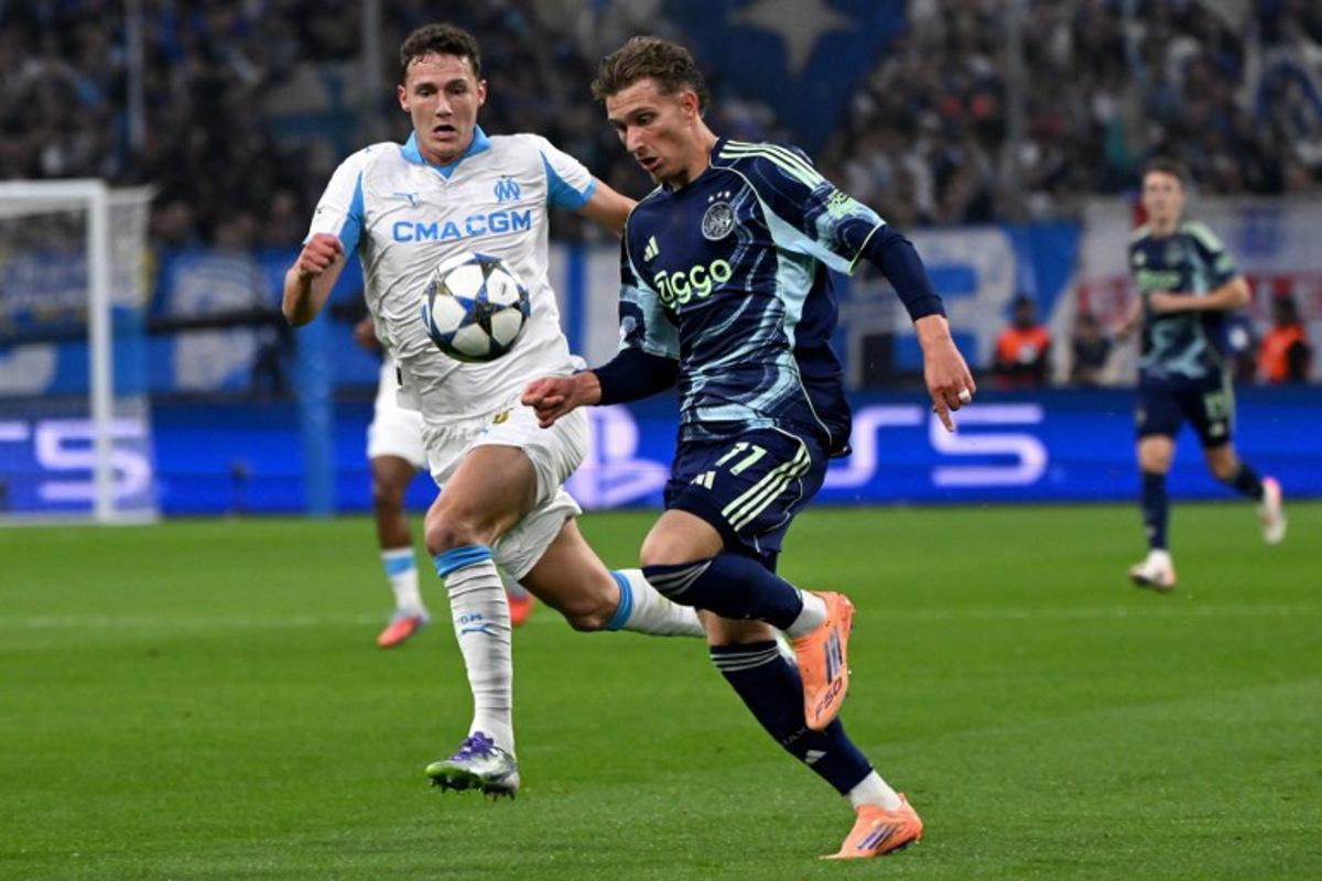 Marseille's French defender #28 Benjamin Pavard (L) and Ajax's Belgian forward #11 Mika Godts fight for the ball during the UEFA Champions League, league phase day 2, football match between Olympique de Marseille (FRA) and AFC Ajax (NED) at the Velodrome stadium, in Marseille on September 30, 2025. Miguel MEDINA / AFP