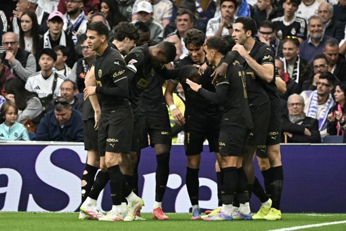 Valencia players celebrate scoring their first goal during the Spanish league football match between Real Madrid CF and Valencia CF at the Santiago Bernabeu stadium in Madrid on April 5, 2025. JAVIER SORIANO / AFP