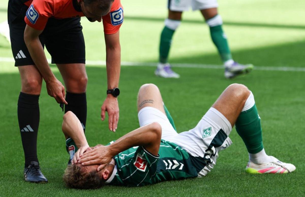 Bremen's Belgian midfielder #14 Senne Lynen lies on the pitch during the German first division Bundesliga football match between Werder Bremen and Bayer Leverkusen in Bremen on August 30, 2025. Ibrahim OT / AFP