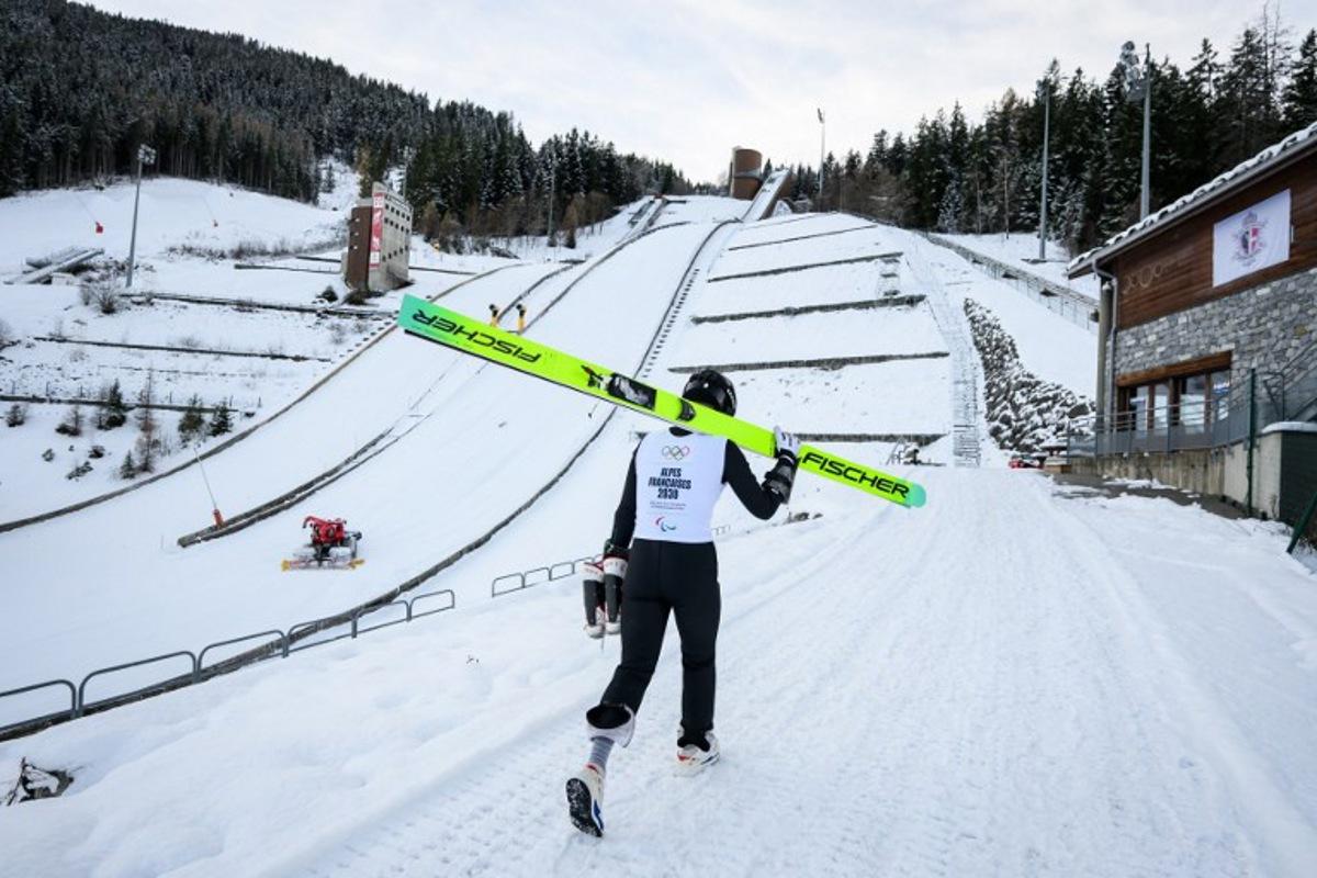 A young athlete walks next to the ski jump in Courchevel, which is set to host the ski jumping competitions at the 2030 Winter Olympics, in Courchevel La Praz, central-eastern France on December 2, 2025. ARNAUD FINISTRE / AFP