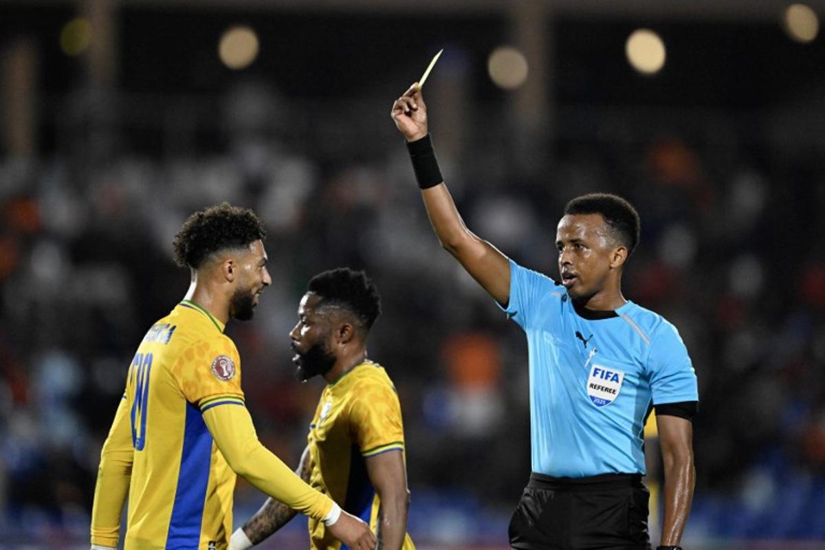 Gabon's forward #20 Denis Bouanga is shown the yellow card by Somali referee Omar Abdulkadir Artan during the Africa Cup of Nations (CAN) Group F football match between Gabon and Ivory Coast at the Grand Stadium in Marrakech on December 31, 2025. Khaled DESOUKI / AFP