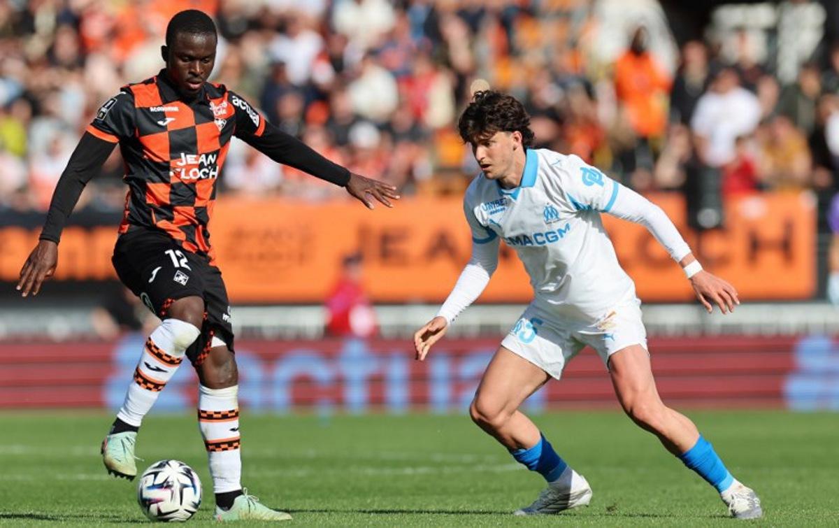 Lorient's Senegalese forward #12 Bamba Dieng (L) fights for the ball with Marseille's Argentinian defender #05 Leonardo Balerdi during the French L1 football match between FC Lorient and Olympique de Marseille at the Moustoir stadium in Lorient, western France on April 18, 2026. Fred TANNEAU / AFP