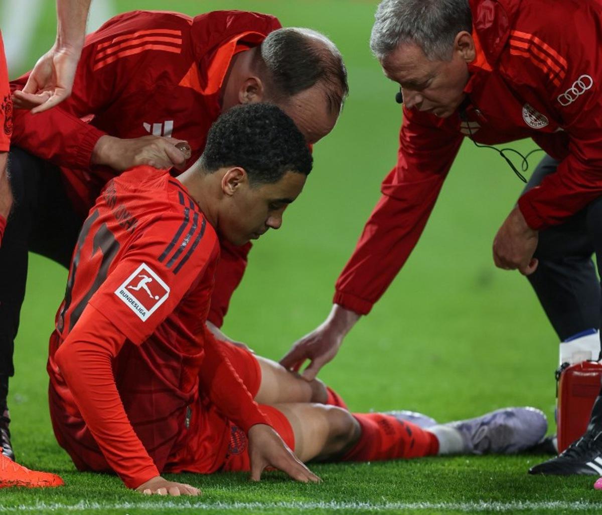 Bayern Munich's German midfielder #42 Jamal Musiala receives medical attention after sustaining an injury during the German first division Bundesliga football match between FC Augsburg and FC Bayern Munich in Augsburg, southern Germany, on April 4, 2025. Alexandra BEIER / AFP