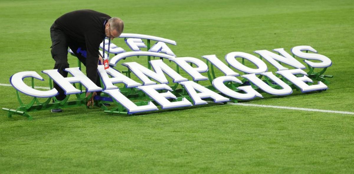 A worker sets up the 'UEFA - Champions League' logo on the field prior to the start of the UEFA Champions League quarter-final second leg football match between FC Bayern Munich and Real Madrid in Munich, southern Germany, on April 15, 2026. Karl-Josef HILDENBRAND / AFP