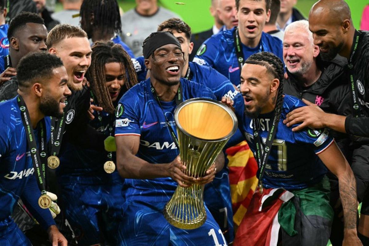 Chelsea's English midfielder #11 Noni Madueke holds the trophy as Chelsea's players celebrate after the UEFA Conference League final football match between Real Betis and Chelsea FC in Wroclaw on May 28, 2025. Sergei GAPON / AFP