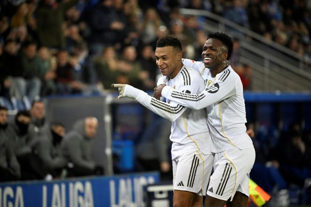 Real Madrid's French foward #10 Kylian Mbappe celebrates scoring his team's first goal with Real Madrid's Brazilian forward #07 Vinicius Junior during the Spanish league football match between Deportivo Alaves and Real Madrid CF at the Mendizorroza stadium in Vitoria on December 14, 2025. ANDER GILLENEA / AFP