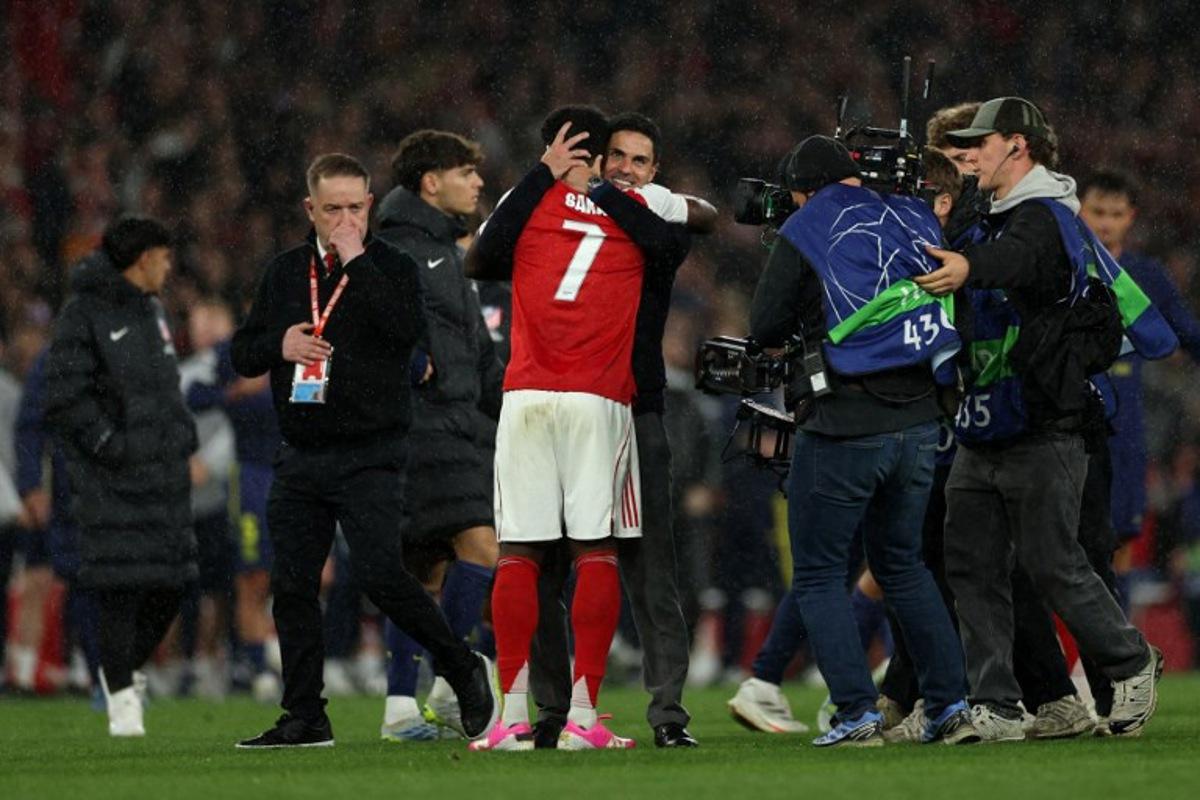 Arsenal's Spanish manager Mikel Arteta hugs Arsenal's English midfielder #07 Bukayo Saka after winning the UEFA Champions League second-leg semi-final football match between Arsenal and Atletico Madrid at the Emirates Stadium in north London on May 5, 2026. Adrian Dennis / AFP