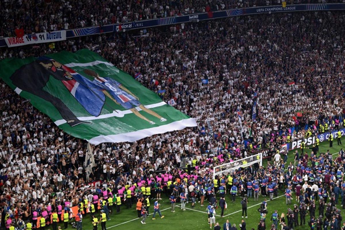 Paris Saint-Germain fans display a banner in the tribunes depicting Paris Saint-Germain's Spanish head coach Luis Enrique planting a flag for his late daughter Xana after the UEFA Champions League final football match between Paris Saint-Germain (PSG) and Inter Milan in Munich, southern Germany on May 31, 2025. Kirill KUDRYAVTSEV / AFP