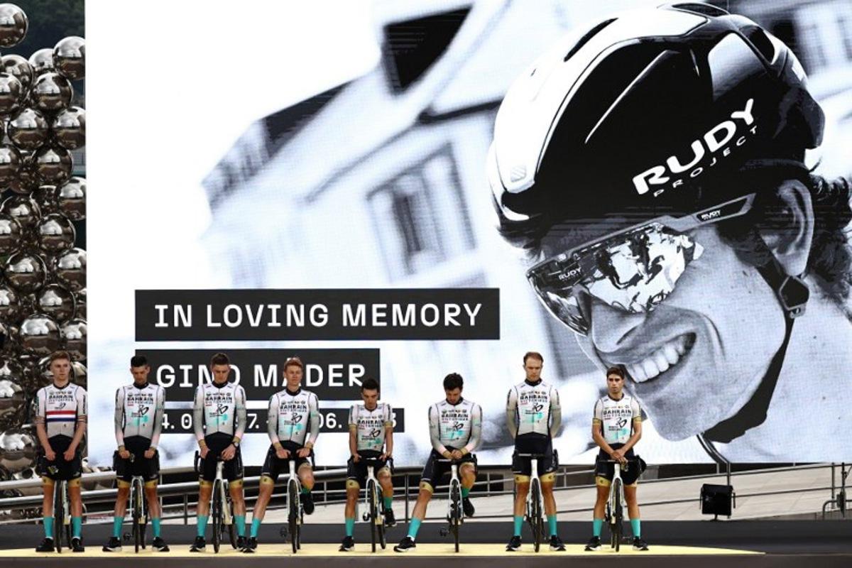 Bahrain Victorious team riders pay tribute to their late teammate, Swiss rider Gino Mader (pictured on screen) during the official teams presentation near the Guggenheim Museum Bilbao, in Bilbao, northern Spain, on June 29, 2023, two days prior to the start of the 110th edition of the Tour de France cycling race. Anne-Christine POUJOULAT / AFP